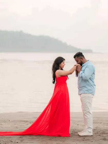 A gentle kiss and a flowing red gown make for a perfect beach pre-wedding photo. The long trail adds a touch of romance and elegance to this sweet moment.