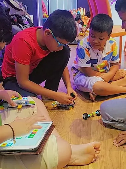 Students collaborating on the floor, testing their code and making adjustments to their robotic cars.