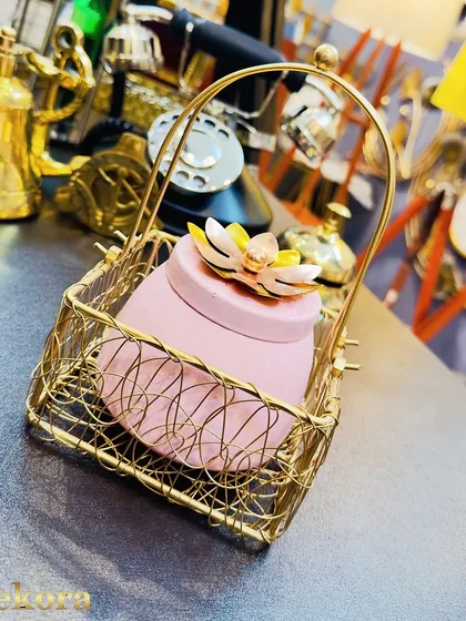 A charming gift option featuring a pink jar with a floral lid, presented in a golden wireframe basket. This is a delicate and modern choice for employee appreciation or client gifting.