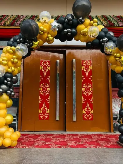 A grand entrance balloon arch in black and yellow for a special event.