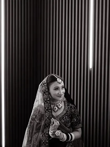 A modern and graphic bridal portrait in black and white. The vertical lights in the background create a striking contrast with the bride's traditional attire.