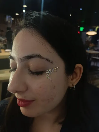 I call this the angel wing design. It's a soft, ethereal look created with pearls and iridescent rhinestones that cascade down the cheek.