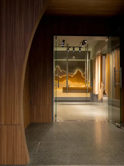 The entrance to the showroom is designed to be dramatic and inviting, with a curved wooden archway framing the view of the artistic installations within.