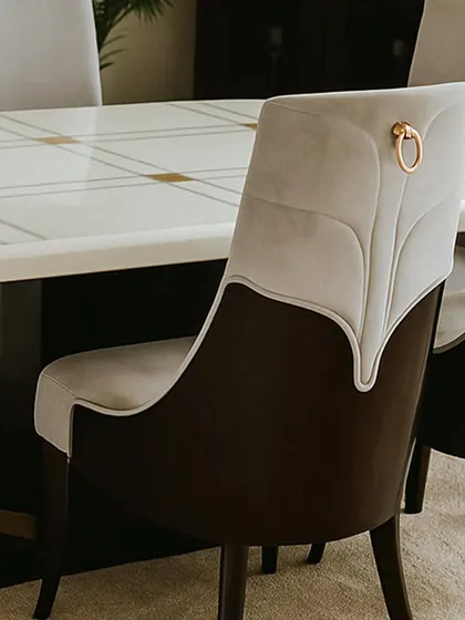 Detail is key in luxury furniture. This close-up shows the back of a dining chair, featuring elegant two-tone upholstery with stitched leaf-like patterns and a decorative metal ring pull. It’s these small, thoughtful touches that elevate a simple chair into a statement piece.