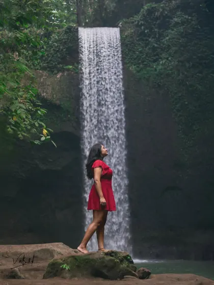 A powerful solo shot at Tibumana Waterfall. The contrast of the red dress against the lush greens and cascading water creates a striking, memorable portrait. I guide my clients to find poses that feel natural yet heroic.