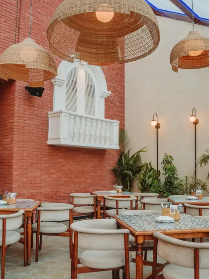 This seating area combines exposed red brick with a whimsical, European-inspired faux balcony. This playful detail adds a touch of old-world romance and serves as a unique photo opportunity for guests.