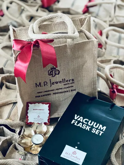 A complete corporate return gift set, including a custom jute bag, a vacuum flask set, and a beautiful lotus diya.