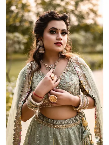 A detailed close-up of the woman in the elegant pastel green lehenga. This shot focuses on her expressive look and the intricate details of her outfit and jewelry.