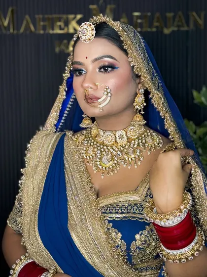 A side profile of the Rajputi bride, showcasing her elegant bun, traditional jewelry, and the flawless finish of her HD makeup against the studio backdrop.