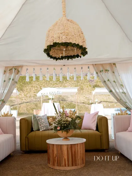 A chic lounge area under a tent for a Mayra ceremony. The olive green and pale pink sofas, paired with a modern wooden table, create a comfortable and stylish space for guests.