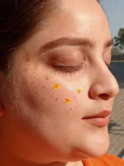 A close-up of tiny, delicate yellow flowers painted on the cheek, giving a sun-kissed, freckled look.