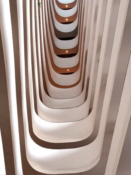 This abstract view shows the rhythmic pattern of the balconies overlooking the central courtyard at the Surat Diamond Bourse. The flowing, organic forms create a sense of movement and connection between the different levels of the world's largest office building.