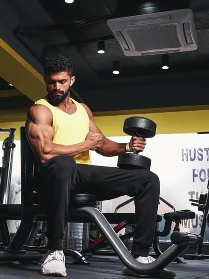 Performing a seated dumbbell curl, a fundamental exercise for building bicep peaks. Proper form, as shown here, is essential for isolating the muscle and preventing injury.