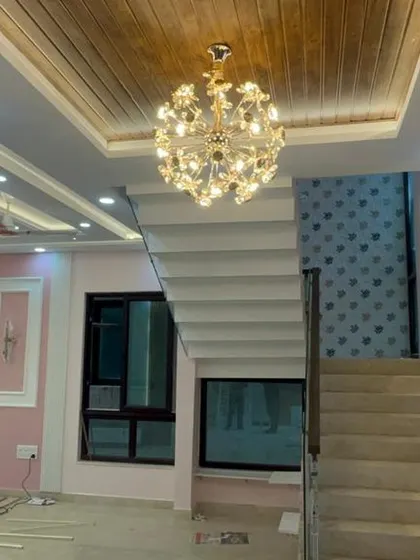 Another angle of the villa interior, showing the interplay between different ceiling heights and lighting fixtures. The design uses both chandeliers and recessed spotlights to create layers of light.