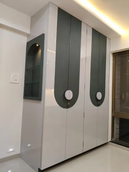 A unique wardrobe design with curved, semi-circular handles and an integrated open-shelf niche for displaying decor.
