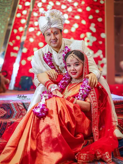 A classic seated portrait of the couple on the wedding stage. They look regal and happy in their beautiful traditional attire.