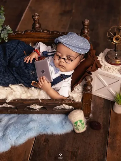 A modern take on a newborn portrait. This little one is styled like a tiny professional, relaxing on a mini-daybed with a miniature laptop and a cup of coffee.
