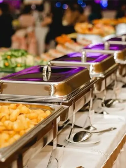 Food should be a feast for the eyes too. This is a snapshot of an elegant buffet arrangement, showcasing a variety of dishes in professional chafing dishes, ensuring the food stays warm and is presented beautifully for a large gathering.