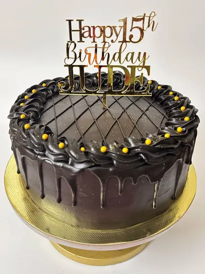 A rich chocolate drip cake for a 15th birthday. The design is simple but decadent, with a glossy drip, piped swirls, and a touch of gold.