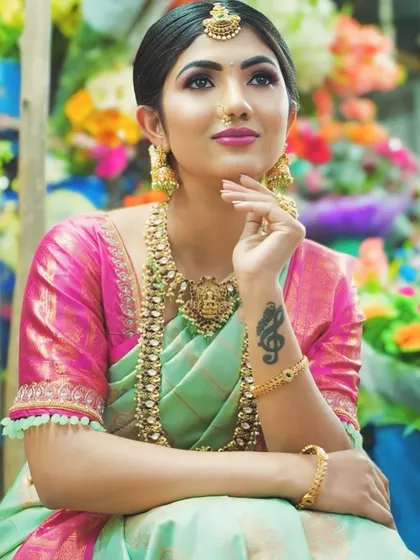 A happy bride showing off her complete look. The antique gold jewellery, including the layered necklaces and jhumkas, perfectly matches her traditional silk saree.