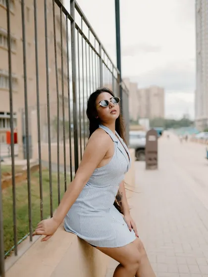 A stylish portrait of a model sitting on a ledge in the city. Her pose and the urban background create a chic and contemporary fashion shot.
