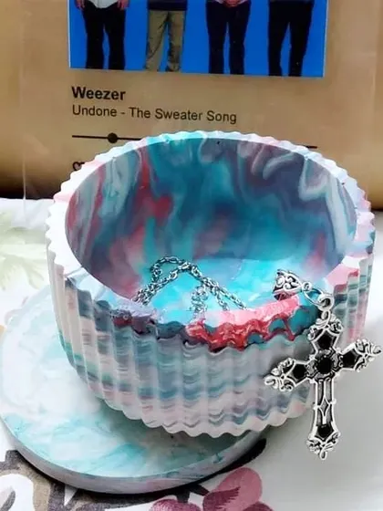 This is our Aurora bowl, a custom piece we made for a client. The swirling blend of colors was inspired by the northern lights. It's shown here being used as a jewelry holder.