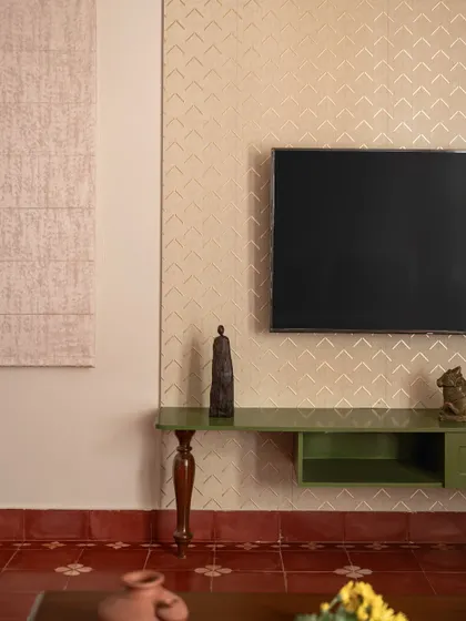 A detail from the 'Varnika' project, this TV unit features a unique leg made from a repurposed wooden element. The green finish and gold-patterned wallpaper reflect the home's Indo-contemporary maximalist style.