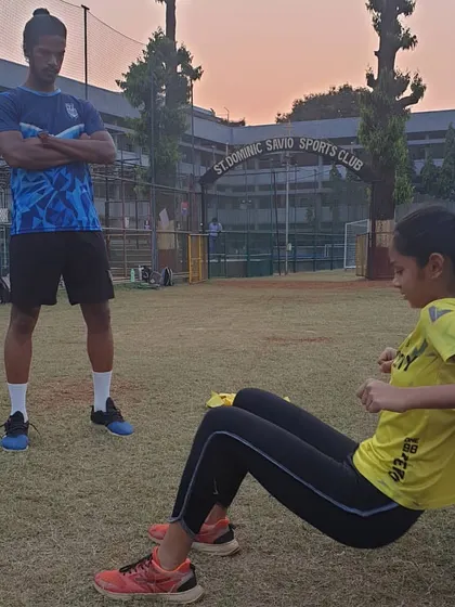 A coach supervises an athlete performing a hip thrust, a key exercise for strengthening the glutes which are critical for running and jumping power.