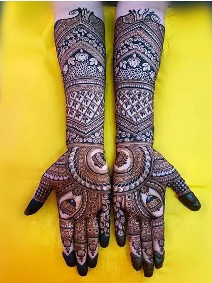 A symmetrical design with a central mandala on the palm, surrounded by intricate patterns. The forearms feature a beautiful blend of jaal work and floral bands.
