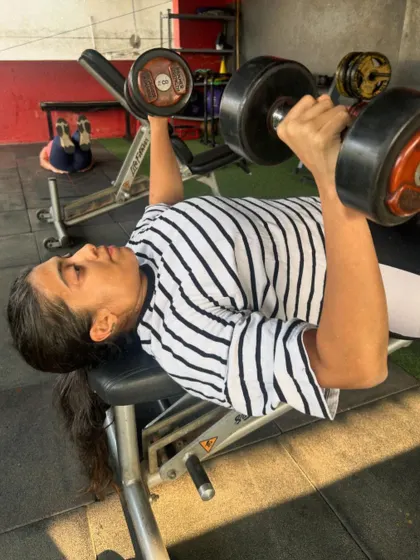 A client performs a dumbbell press on a bench, a versatile exercise for chest development.