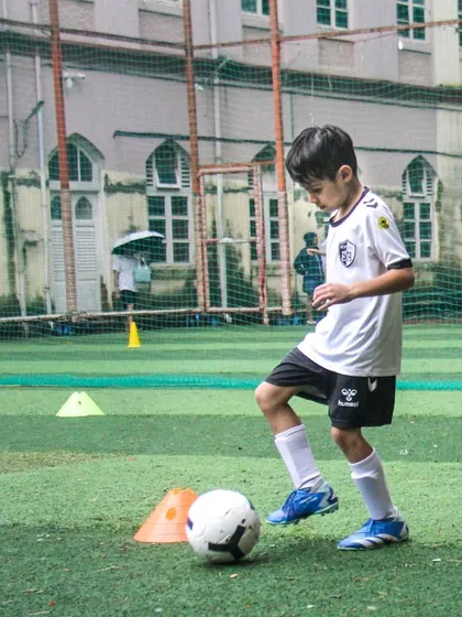 A young player practices dribbling with his eyes up, a critical skill for developing game awareness that we emphasize in our coaching.