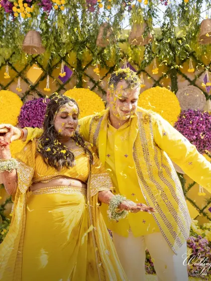 The couple dancing together during their Haldi, covered in flowers and happiness.