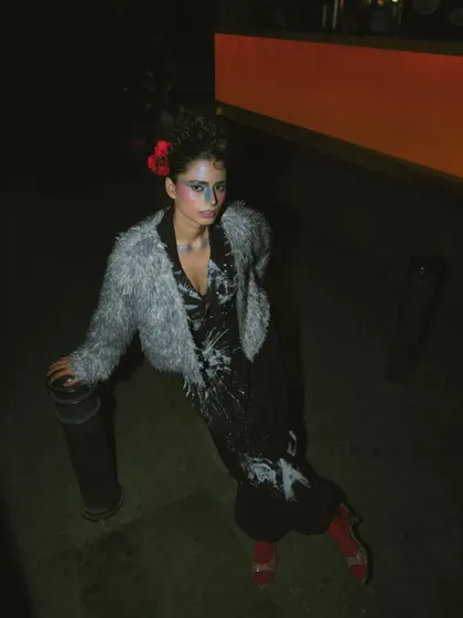 Part of the 'Lampione' night series, this look combines a faux fur jacket with a graphic print outfit. The styling and dramatic makeup were designed to capture a moody, urban, and artistic vibe.