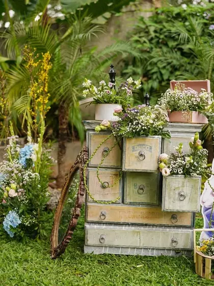 A quirky decor corner with a vintage chest of drawers, with flowers spilling out of it, and a cutout of the White Rabbit, adding to the Wonderland theme.