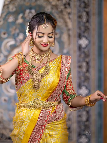 This bride looks like a queen in her yellow silk saree and full temple jewellery set. The peacock-motif Vaddanam is a special piece from my collection.