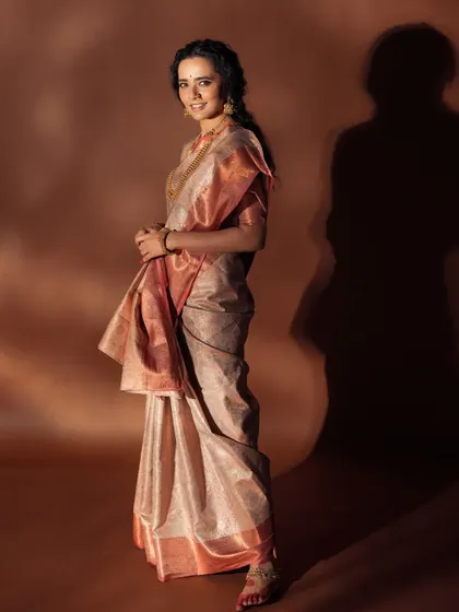 A full-length profile shot showing the beautiful drape of the saree. The hairstyle is a loose, traditional braid, which works beautifully with the overall aesthetic.