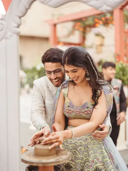 A couple gets their hands dirty at a live pottery station during their Parisian-themed Mehendi. Interactive activities like this are a great way to engage guests and create lasting memories.