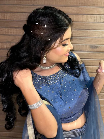This shot highlights the hairstyle that accompanies the party makeup, featuring soft waves and delicate pearl accessories.