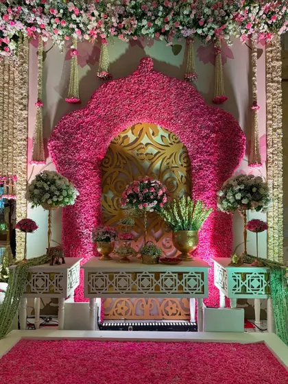 An opulent photo corner, featuring a statement arch of pink flowers, a gold-patterned backdrop, and a floor of fresh petals. It's designed to impress at every glance. 🌸