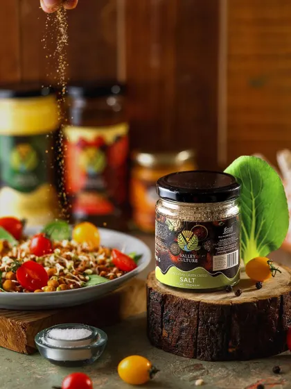 A dynamic shot of Valley Culture's flavored salt being sprinkled over a fresh salad. This action shot demonstrates the product in use, highlighting its role in enhancing healthy and delicious meals.