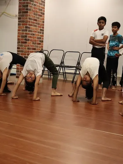 A row of students practicing Chakrasana (Wheel Pose) together, creating a wave of energy and shared effort.