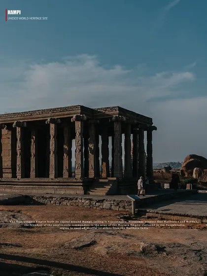 A wide shot of a pillared hall, or mandapa, standing resolute against a backdrop of Hampi's characteristic boulder-covered hills. This photo showcases the unique blend of architecture and nature.