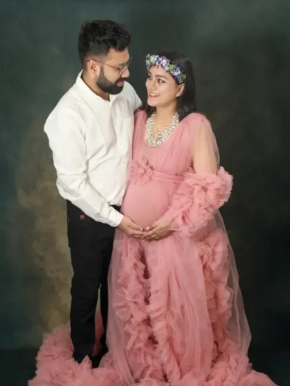 A beautiful couple portrait from a studio session. The mom-to-be is wearing a stunning pink gown, and the way they look at each other is full of love.