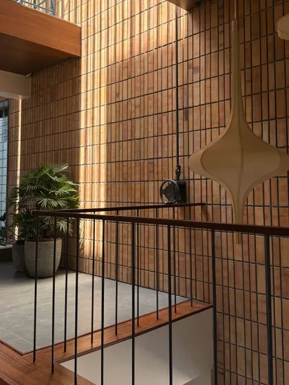 Sunlight grazes a wall of vertically laid bricks, highlighting the rich texture and color variations of the material.
