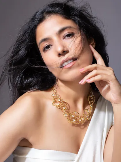 Another angle of the abstract gold necklace, this time with a soft, confident expression to highlight its elegance.
