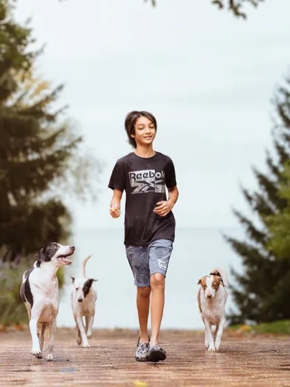 A boy and his pack of three dogs enjoying a run together. This dynamic shot, transformed through editing, captures the energy and joy of being outdoors with your furry best friends.