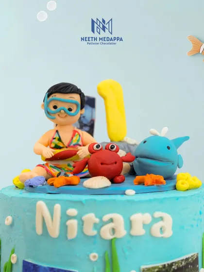 A close-up of the topper on the ocean cake, showing the personalized scuba diver figure, crab, and whale.