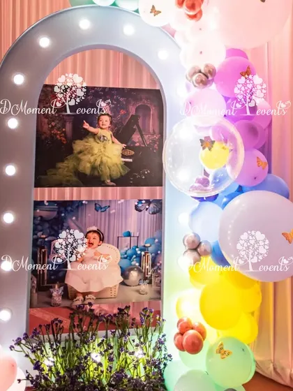 A beautiful light-up arch displaying photos of the birthday girl, decorated with a colorful balloon garland.