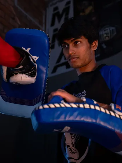 A student holding pads for his training partner, showing intense focus. Holding pads is a skill in itself, and it's a key part of how we train together as a team.