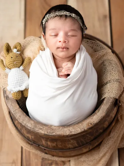 A classic pose in a rustic wooden bucket, with a tiny knitted friend for company. The natural tones and textures create a warm and earthy feel for this newborn photo.